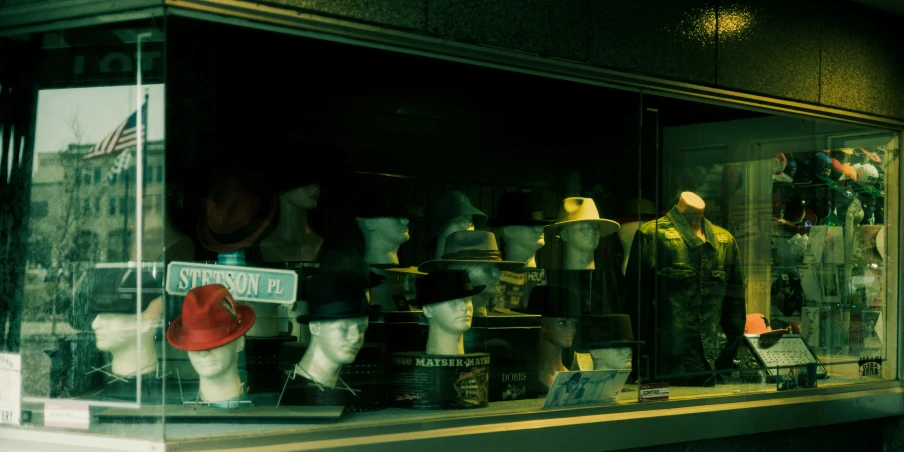 many different hats in a window with lights