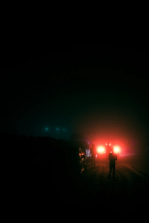 a man stands in the dark with his motorcycle behind him