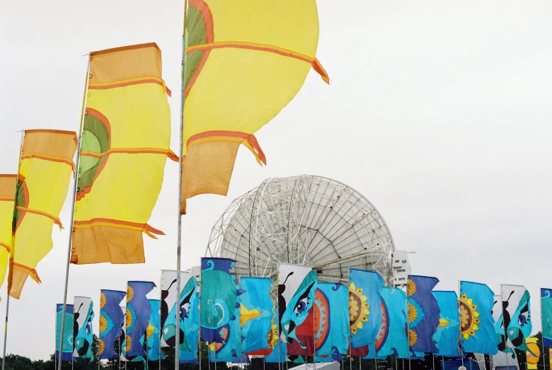 a large array of colorful flags that are in front of a ferris wheel