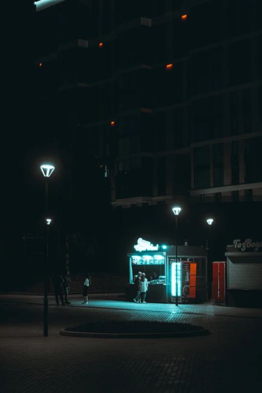 some people in the street at night with a building and bright lights