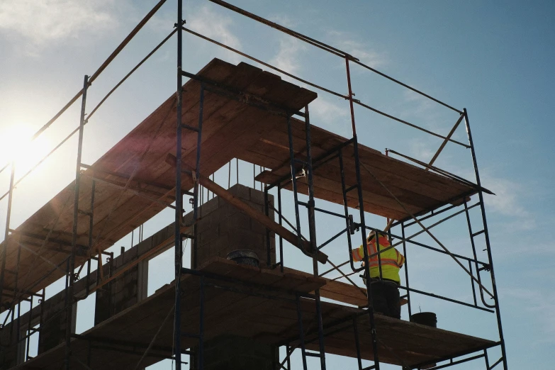 two men in construction equipment on top of scaffolding