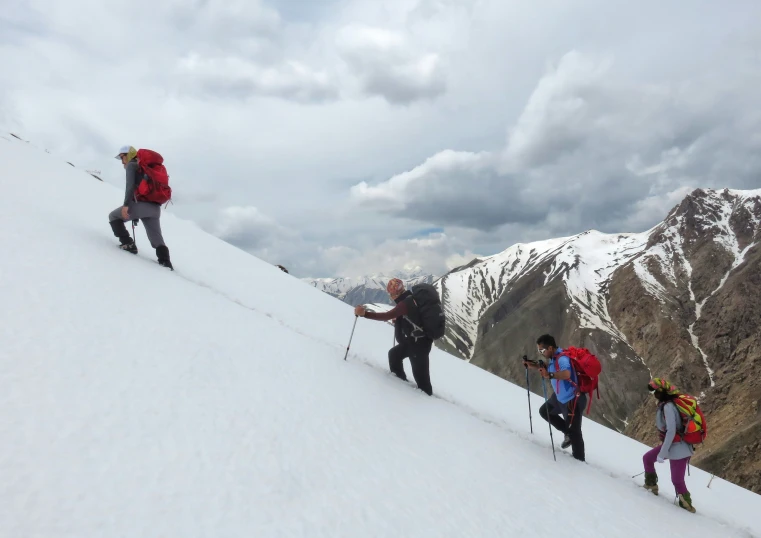 five people on a snowy hill with backpacks