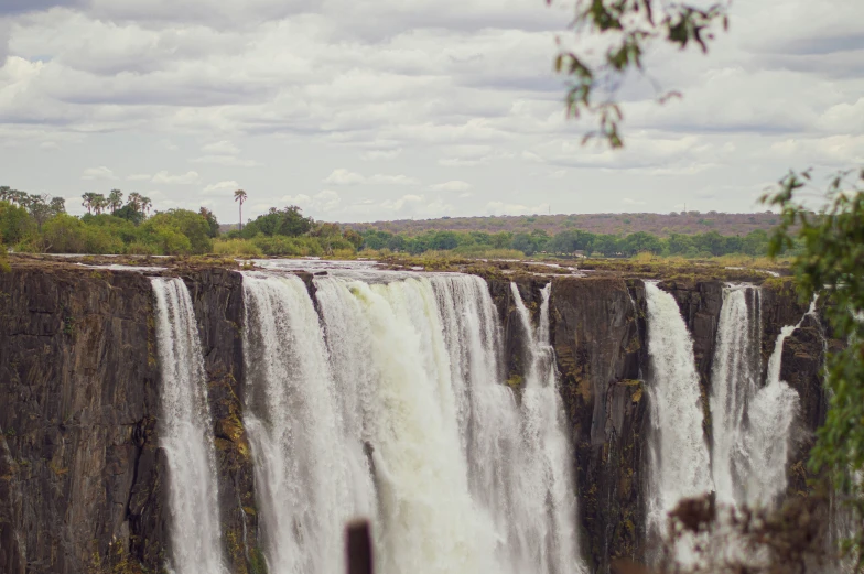 a group of people standing on top of the side of a tall waterfall