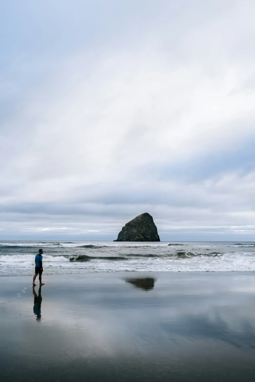 a man walks along the shoreline of a beach