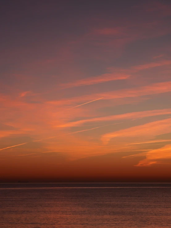 a body of water with a plane flying in the sky