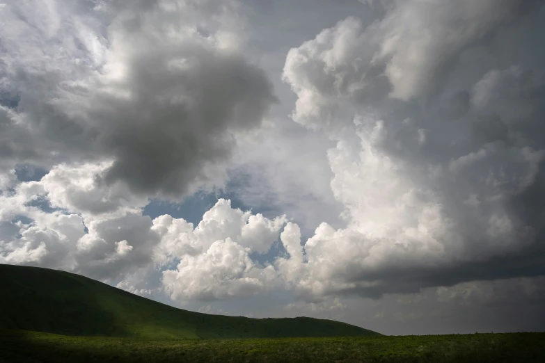 many clouds are coming off the hill on a cloudy day