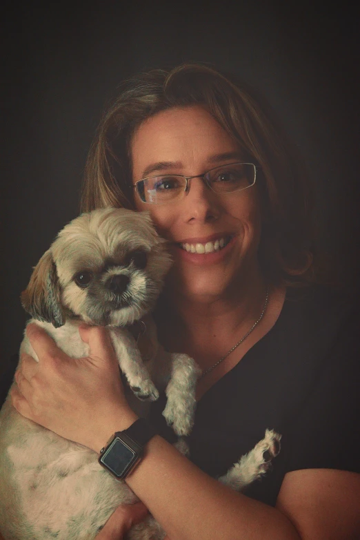 a woman with glasses holding her small puppy