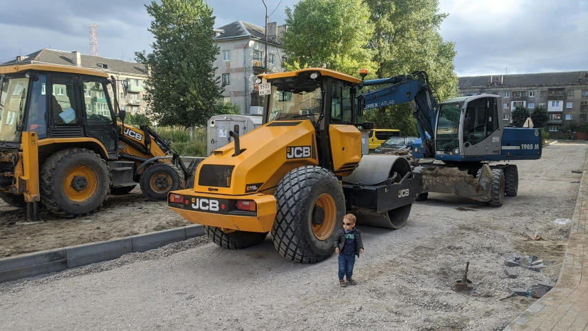 a man stands in front of two large construction vehicles