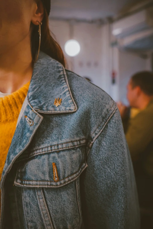 girl in yellow sweater and denim jacket looking down