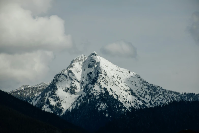 a mountain peak is seen against a cloudy sky