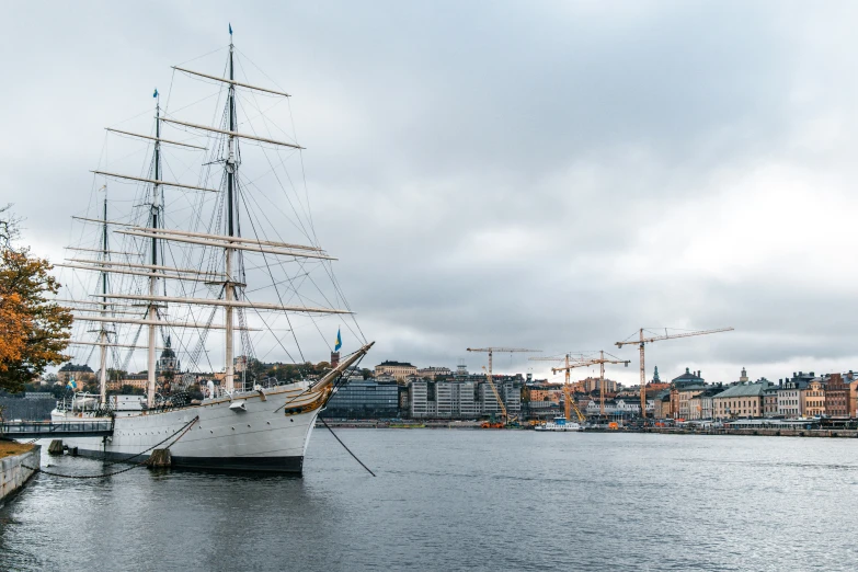 an old sailing ship in the harbor with another boat