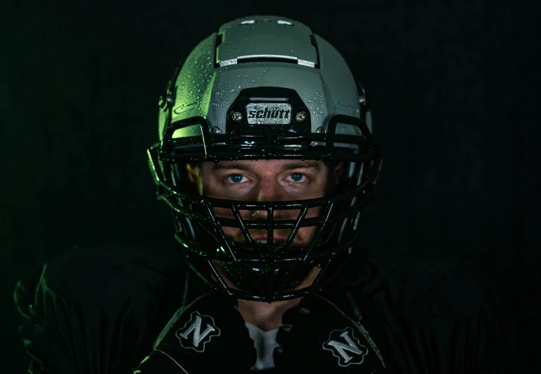 this football player is wearing his helmet in the dark