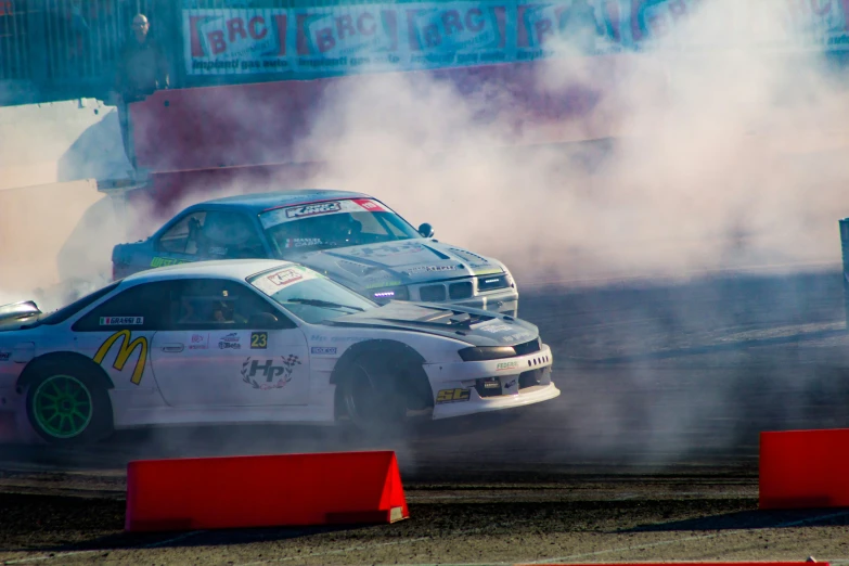 the smoke and dirt are blowing behind two cars