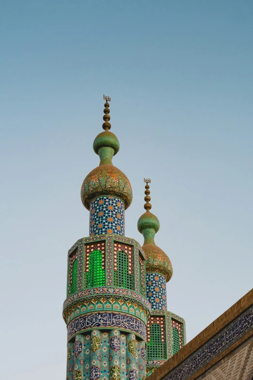 the top of a blue and green building with three towers