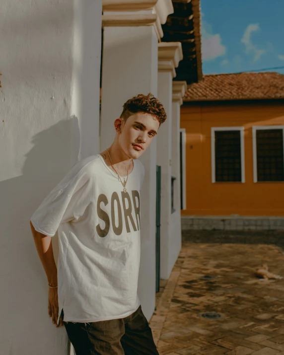 a man posing next to a white wall and a house