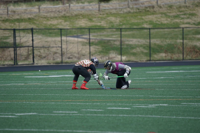 the two lacrosse players are playing in a field