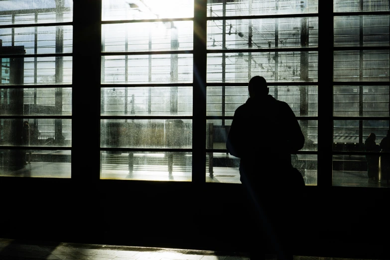 a person stands in a dark room with big windows