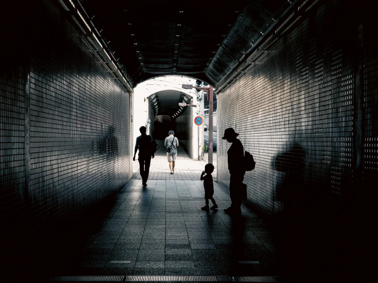 people walking through a dark tunnel towards the camera