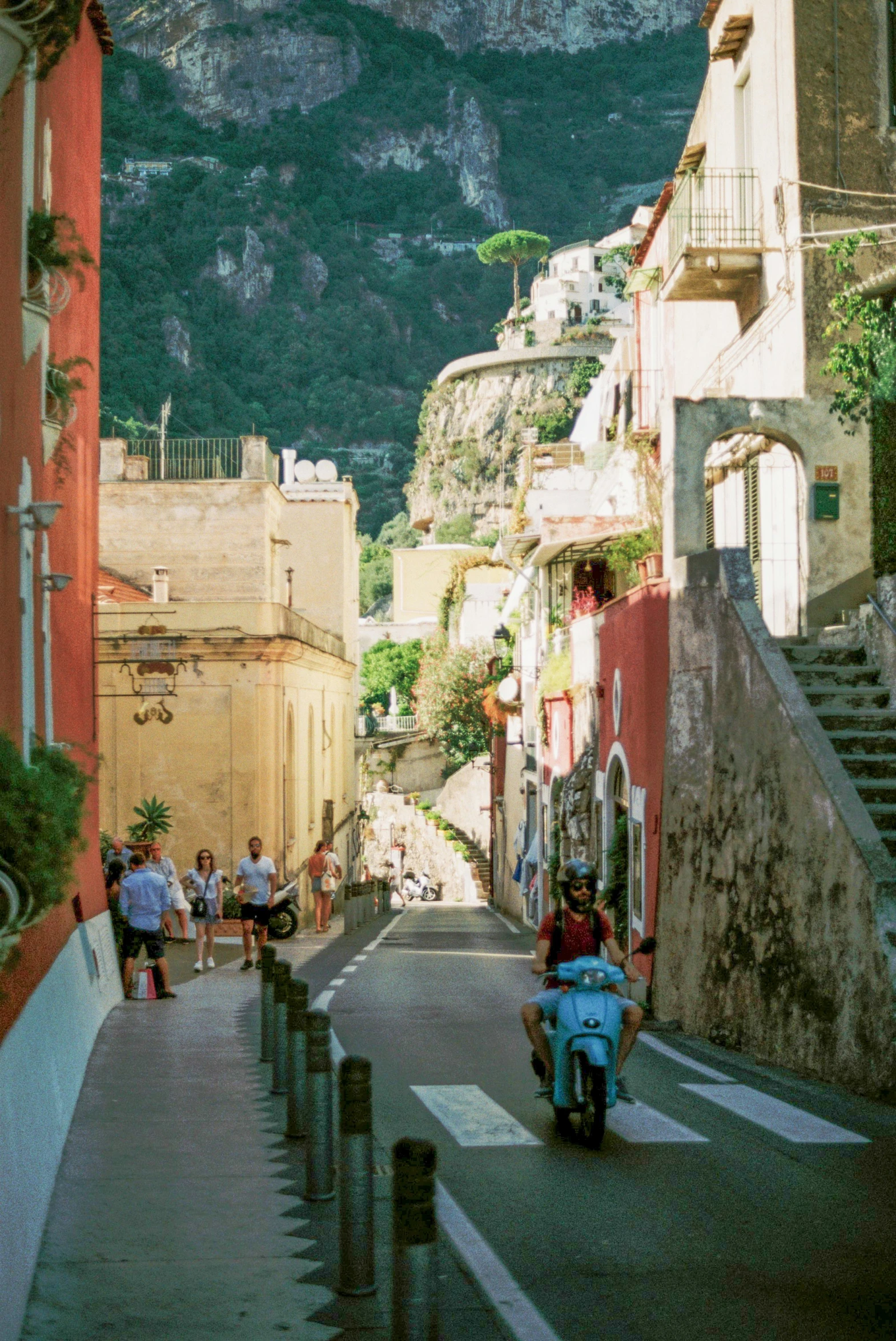 several people walking up a steep street with a scooter