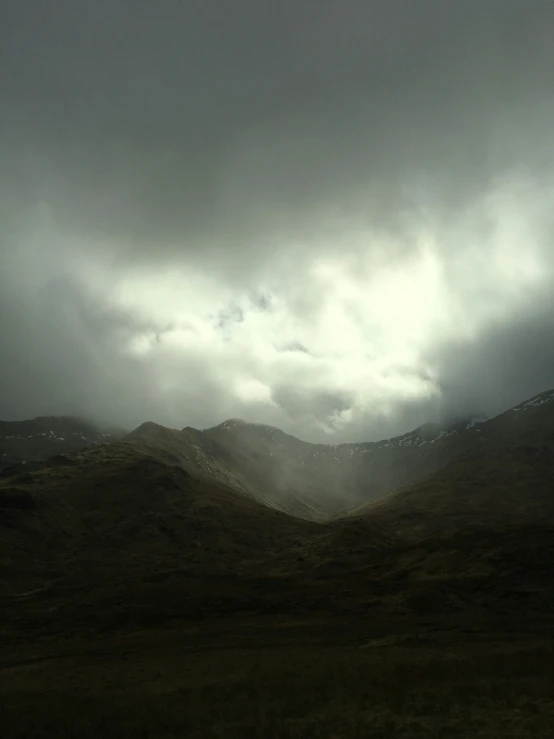 clouds loom over hills on a misty day