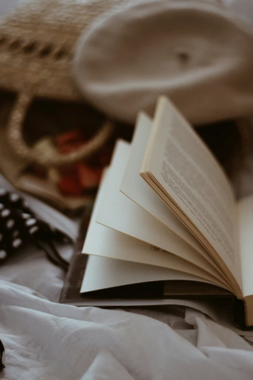 a book open on a bed next to an unmade footbed