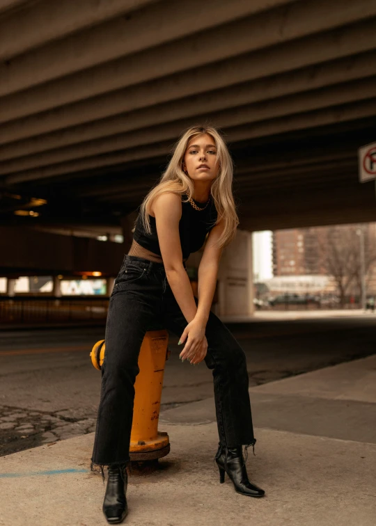 a woman sitting on a yellow fire hydrant wearing black