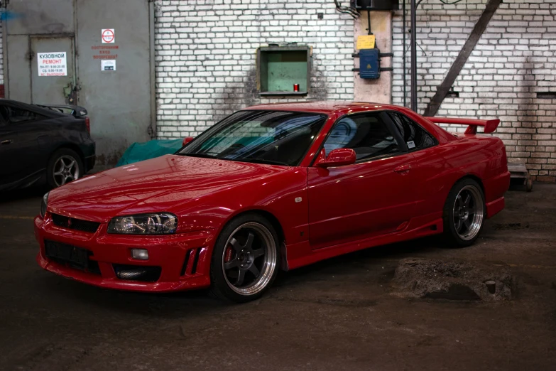 a red sports car parked in front of a brick wall