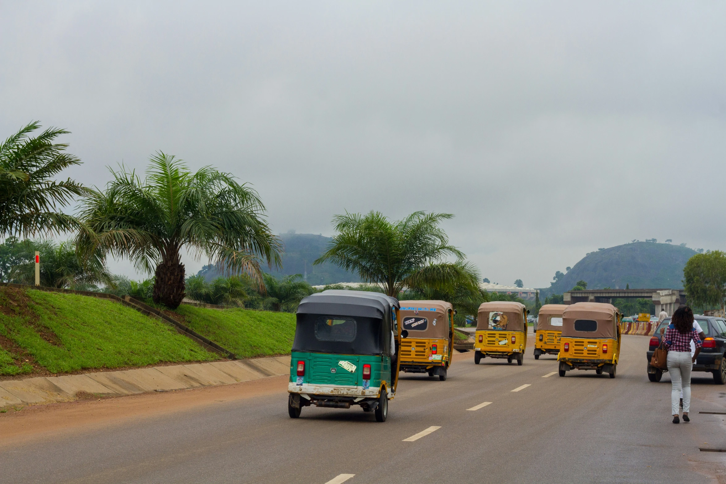 a group of green and yellow three wheeled vehicles traveling down a road