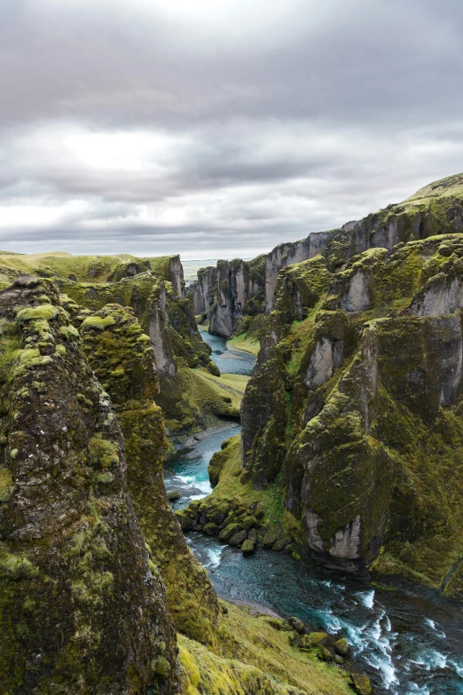 view from the top of some cliffs and blue water in a green valley