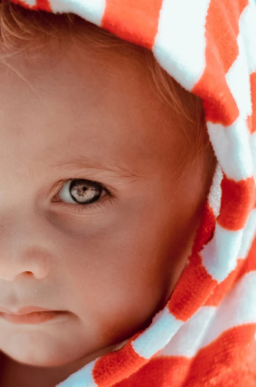 a baby covered in an orange and white blanket