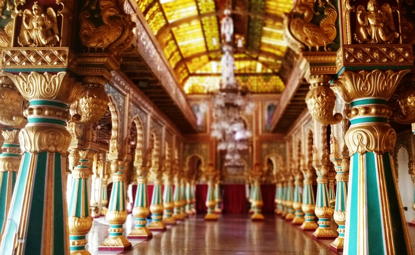 a long hallway with multiple gold pillars and mirrors