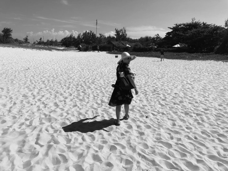 the woman is walking alone in the white sand