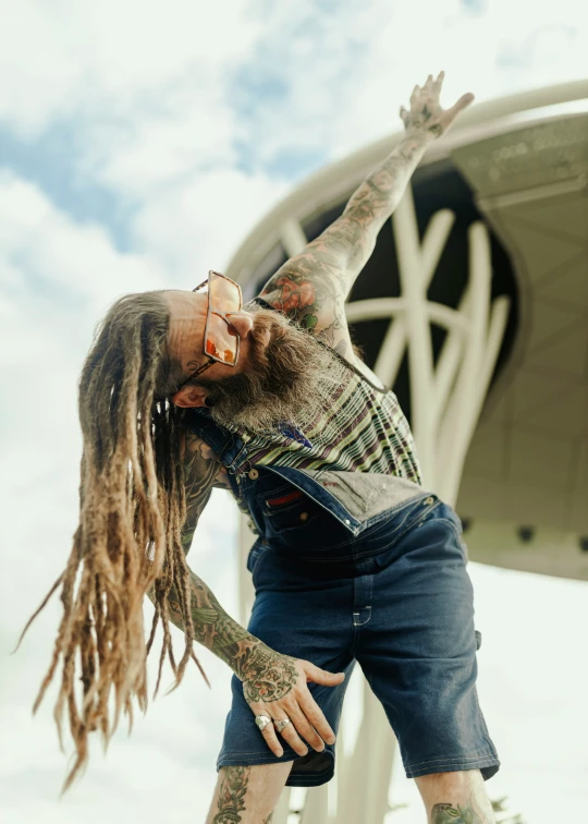 a man with dreads holding his arm up with his hand