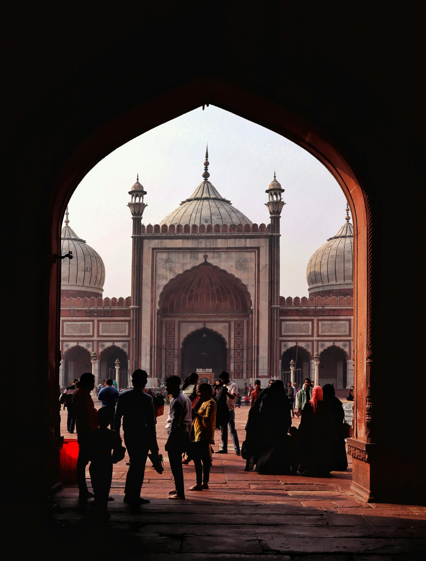 there are people walking through an archway on a street