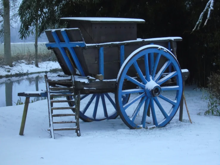 a cart on snow covered ground with wooden wheels