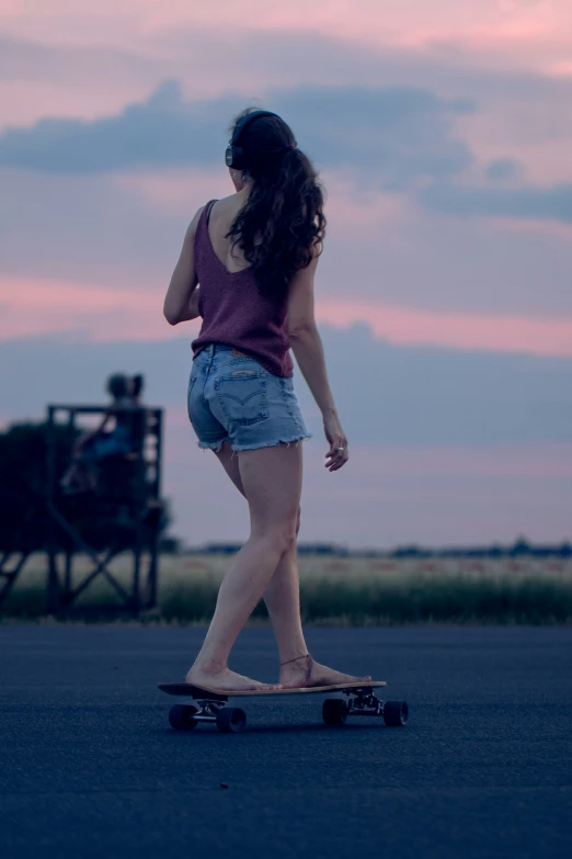 a woman in denim shorts rides a skateboard through the street