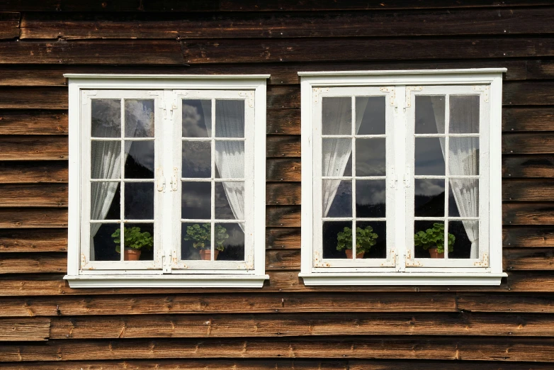 two white windows are opened in a rustic wooden house