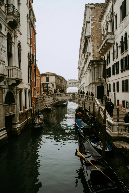 small boats floating down a river between two tall buildings