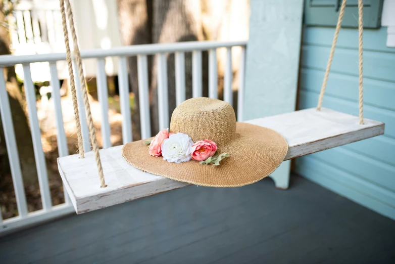 a hat sitting on a swing with flowers