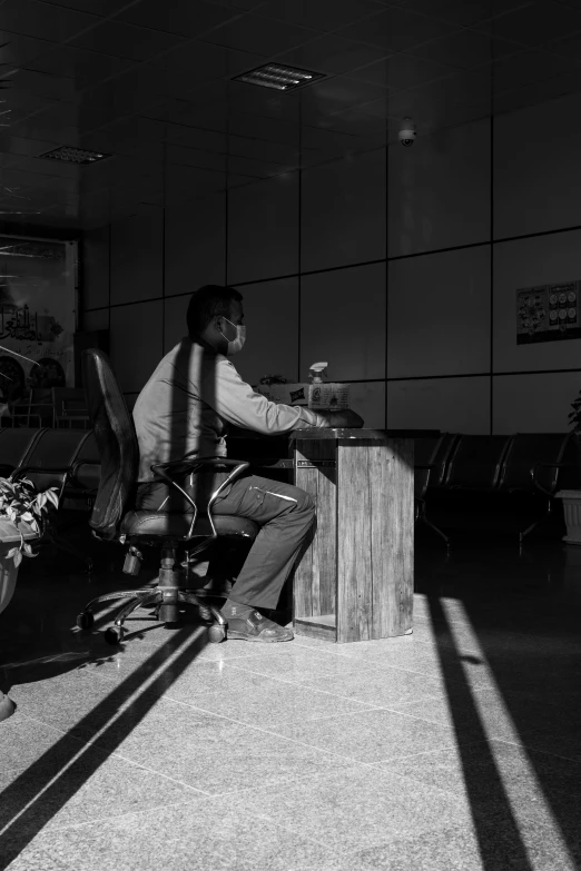 a man sitting at a wooden desk next to a pile of luggage