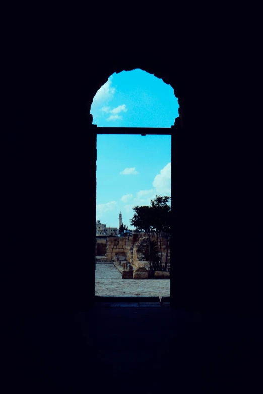 an arch leading into a building with blue sky and clouds above