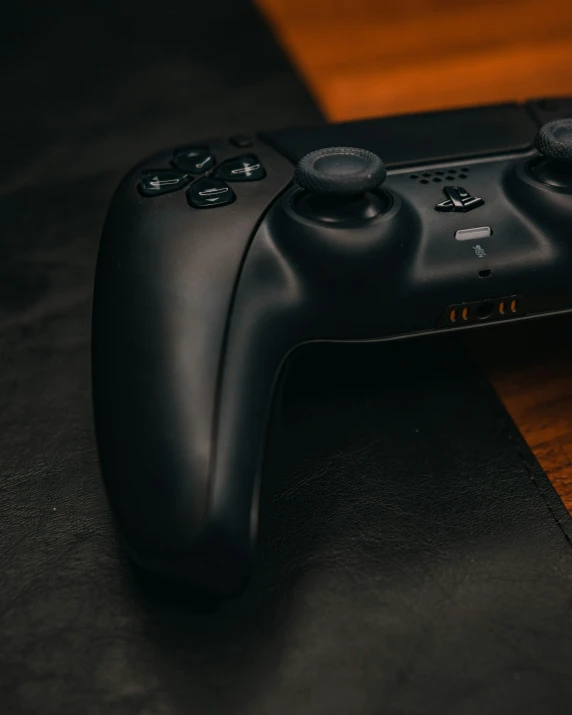 a black game controller sitting on top of a wooden table