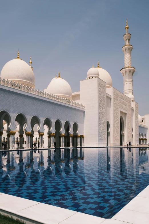 an outdoor pool with a blue tiled pattern and a tall building with domes on it