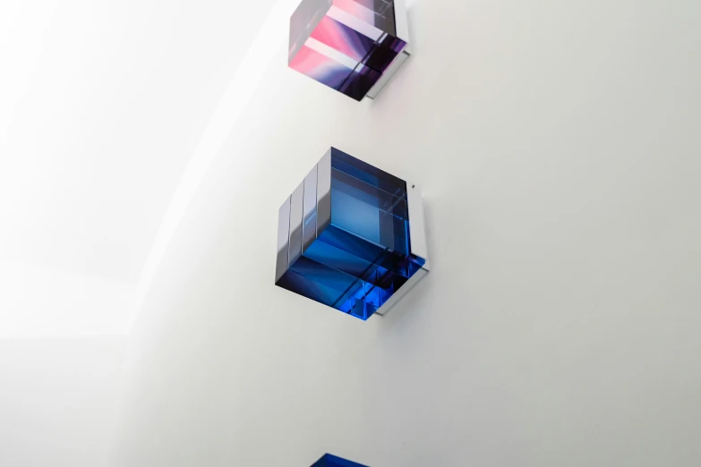 three abstract glass cubes in different angles and sizes on a wall