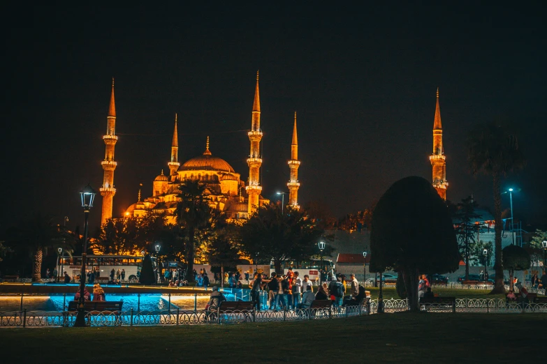 a large building that is at night with people standing on the side of it