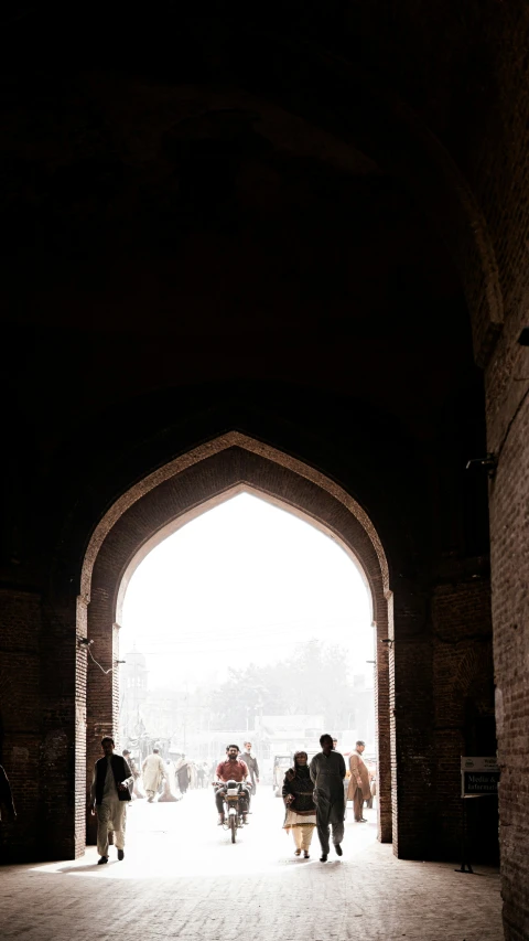 people walking under an arch near the sidewalk