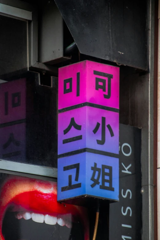 a pink blue purple and black cube hanging on a building