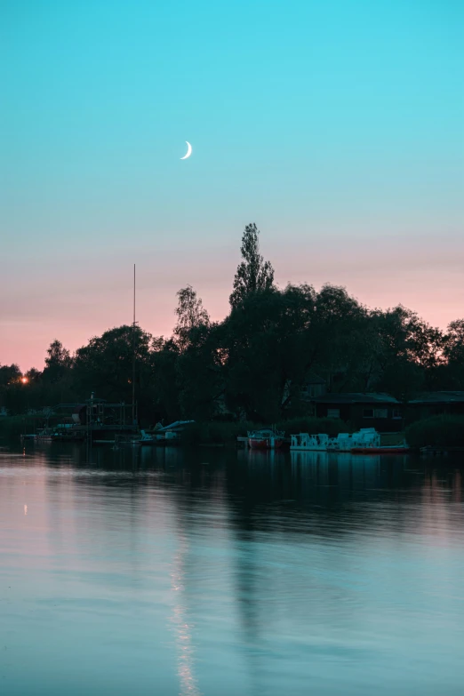 the moon is rising over a calm bay