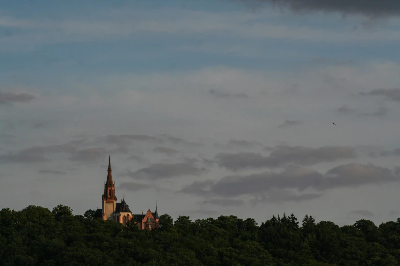 a tall church tower sitting behind green trees