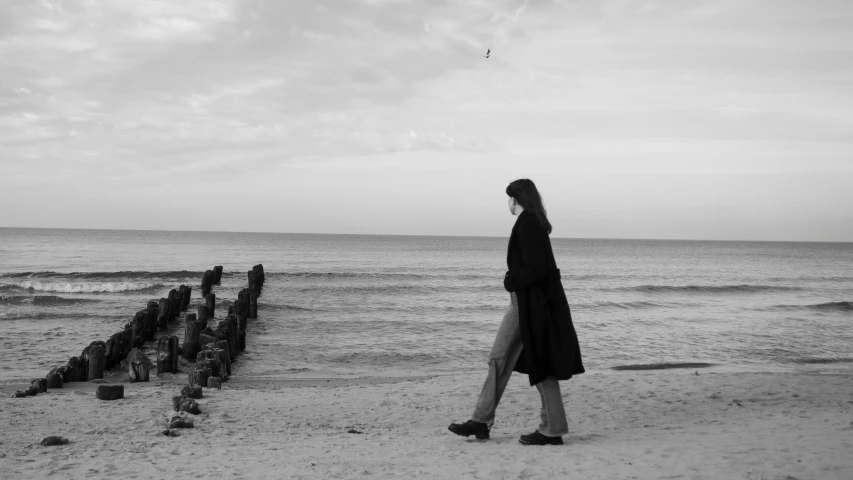 a woman is walking along the beach by the water